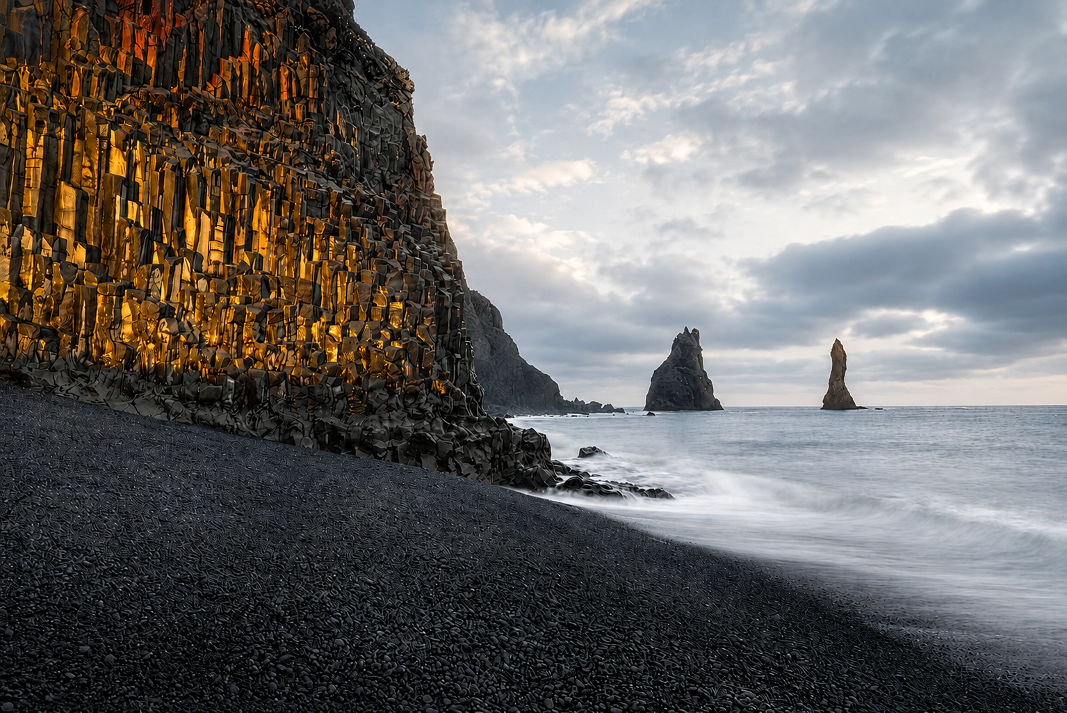 Basalt columns and black volcanic sand on an Icelandic shoreline