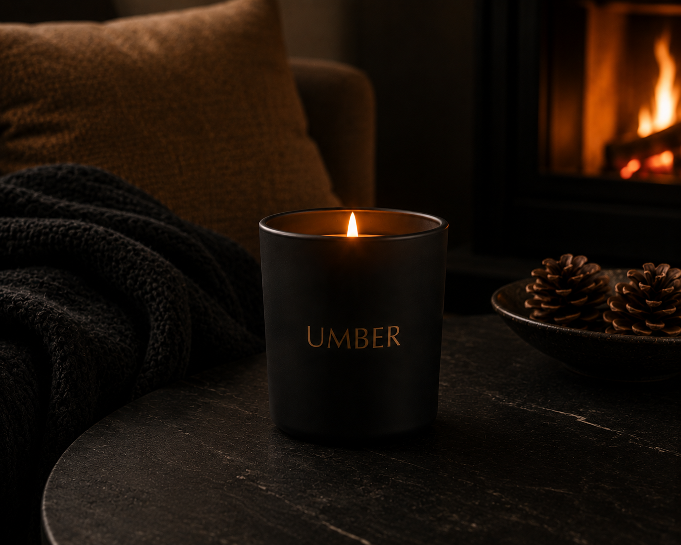 HEARTH candle burning on a dark table beside a fireplace